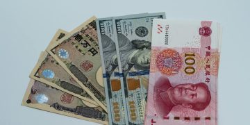 Various international currency notes including US dollars, yen, and yuan arranged on a surface.
