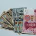 Various international currency notes including US dollars, yen, and yuan arranged on a surface.