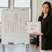 Woman presenting business data on clipboard with success graph in an office.