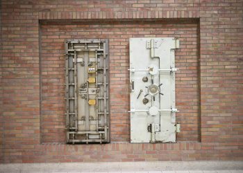 Two steel security vault doors attached to a vintage brick wall, showcasing industrial strength.