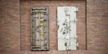 Two steel security vault doors attached to a vintage brick wall, showcasing industrial strength.
