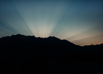 Silhouette of mountains with dramatic rays of sunlight at sunrise.