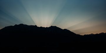 Silhouette of mountains with dramatic rays of sunlight at sunrise.