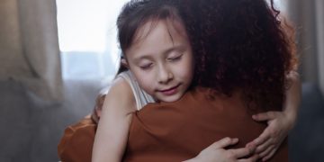 A heartfelt mother-daughter hug indoors, symbolizing love and connection.