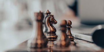 A detailed close-up of chess pieces on a board, highlighting the knight in warm tones.
