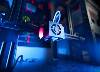 A close-up of an illuminated 3D printer in action, highlighting modern technology.