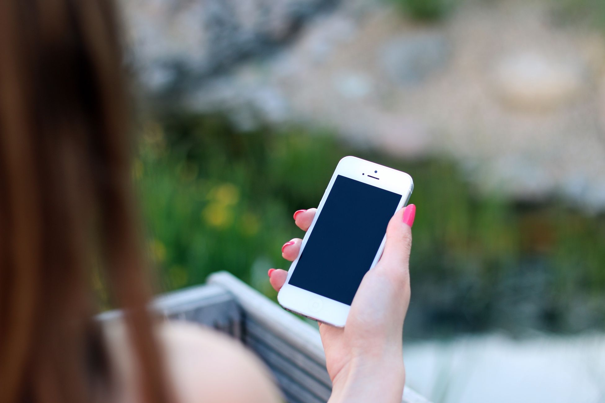 Woman using smartphone with blank screen, perfect for adding graphics. Outdoor lifestyle concept.