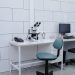 Modern laboratory with microscope, monitor, and office equipment on desk.