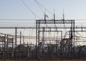 High-voltage electrical substation with steel structures and power lines at dawn.