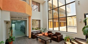 A spacious, modern lobby with high ceilings, large windows, and contemporary furniture.