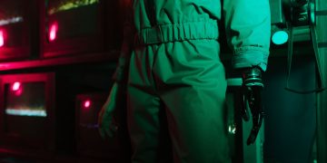 A cyberpunk setting featuring a person with a robotic arm amidst neon and retro elements.