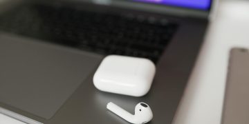 A close-up shot of wireless earbuds and case on a laptop, perfect for tech themes.
