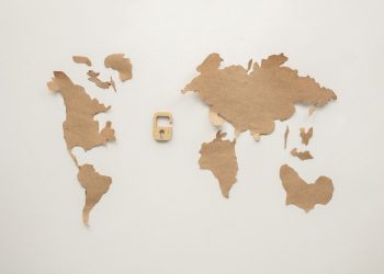An artistic flat lay of a world map cutout accompanied by a padlock, symbolizing security.