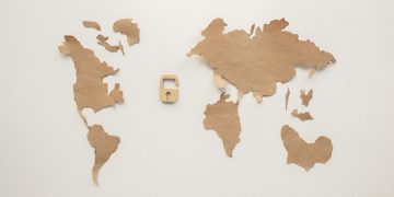 An artistic flat lay of a world map cutout accompanied by a padlock, symbolizing security.