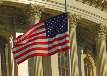 US flag waving outside the iconic US Capitol Building in Washington, DC.