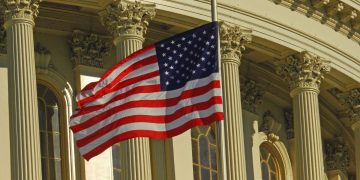 US flag waving outside the iconic US Capitol Building in Washington, DC.