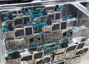 From above of circuit boards of modern smartphones placed in plastic box in electronics factory