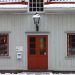Historic wooden house with red doors and snow on the roof, embodying a wintery charm.