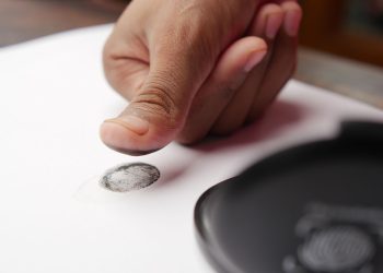 Detailed shot of a thumb creating a fingerprint on white paper, ideal for security themes.