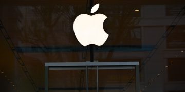 the apple logo is reflected in the glass of a building