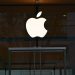 the apple logo is reflected in the glass of a building