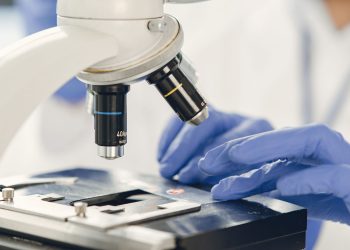 Close-up view of a scientist examining a specimen under a microscope in a laboratory.