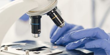 Close-up view of a scientist examining a specimen under a microscope in a laboratory.