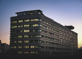 A modern office building beautifully illuminated against the twilight sky in an urban setting.
