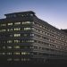 A modern office building beautifully illuminated against the twilight sky in an urban setting.