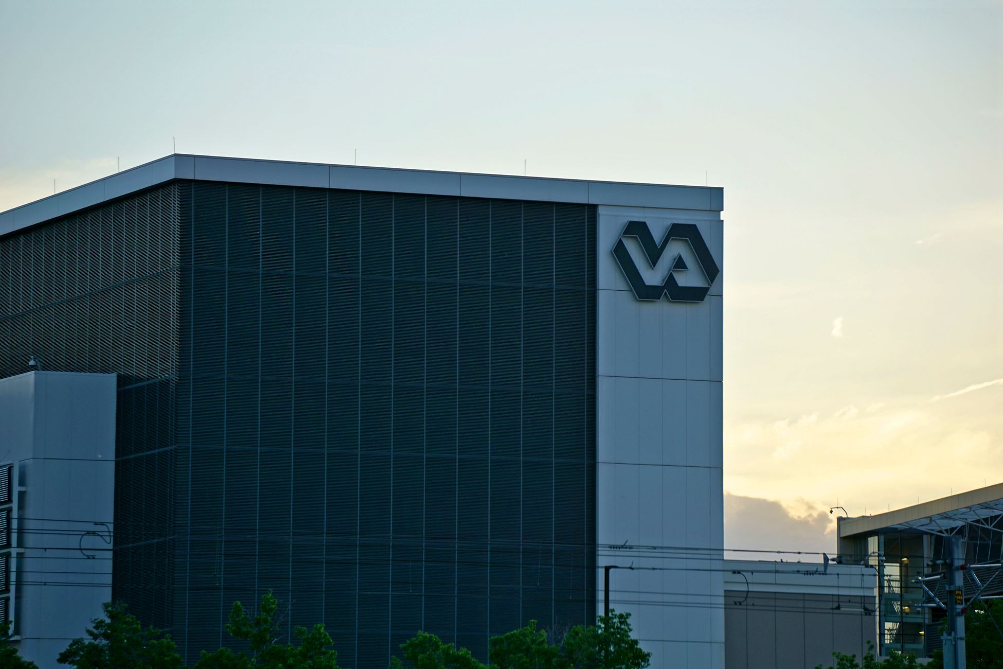 A modern building featuring a prominent VA sign, captured at sunset.