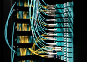 Closeup of electronic device with colorful wires installed in rows in communications room on blurred background in dark studio inside