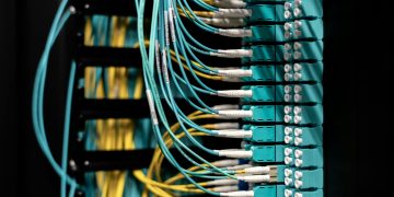 Closeup of electronic device with colorful wires installed in rows in communications room on blurred background in dark studio inside