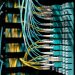Closeup of electronic device with colorful wires installed in rows in communications room on blurred background in dark studio inside