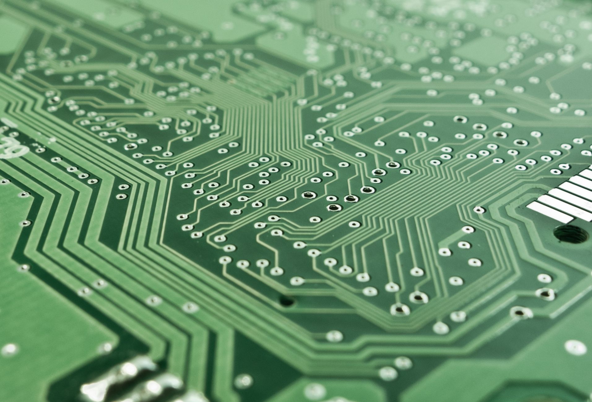 Detailed view of a green circuit board with complex patterns and pathways.