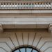 Low angle view of a neoclassical building facade featuring pillars and a balcony in daylight.