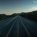 A serene aerial view of an empty mountainous highway at dusk, showing the vastness and tranquility.