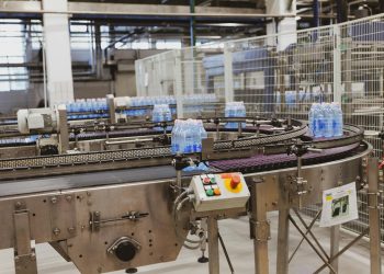 Water bottles being processed on an automated conveyor in a modern factory setting.