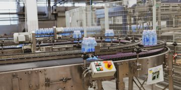 Water bottles being processed on an automated conveyor in a modern factory setting.
