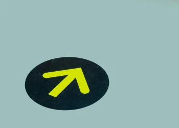 Minimalist image of a yellow arrow on a blue floor indicating direction, ideal for navigation themes.