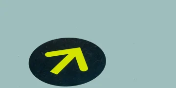 Minimalist image of a yellow arrow on a blue floor indicating direction, ideal for navigation themes.