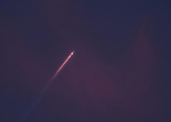 A stunning view of a rocket leaving a fiery trail as it ascends into the night sky.