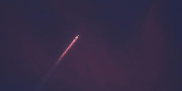 A stunning view of a rocket leaving a fiery trail as it ascends into the night sky.