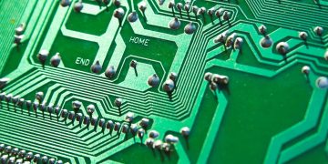 Detailed view of green circuit board with visible chips and pathways, highlighting technology elements.