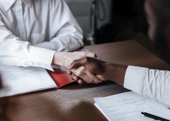 Close-up of a diverse business handshake over documents, symbolizing agreement and collaboration.