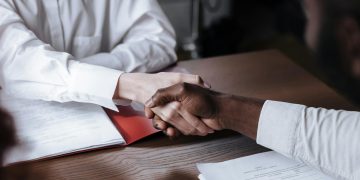 Close-up of a diverse business handshake over documents, symbolizing agreement and collaboration.
