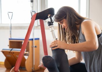 Rehabilitation session indoors focusing on a prosthetic leg exercise with resistance band.