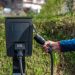 An outdoor electric car charging station with a hand holding a charging cable.