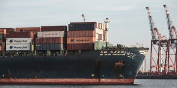 Cargo ship with containers and cranes in Hamburg port.