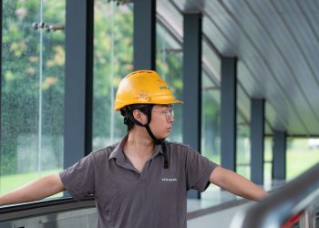 Construction worker in a hard hat examines an industrial site, showcasing safety and industry.