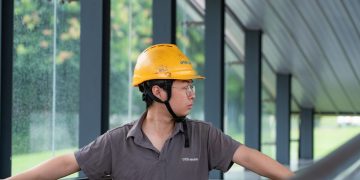 Construction worker in a hard hat examines an industrial site, showcasing safety and industry.